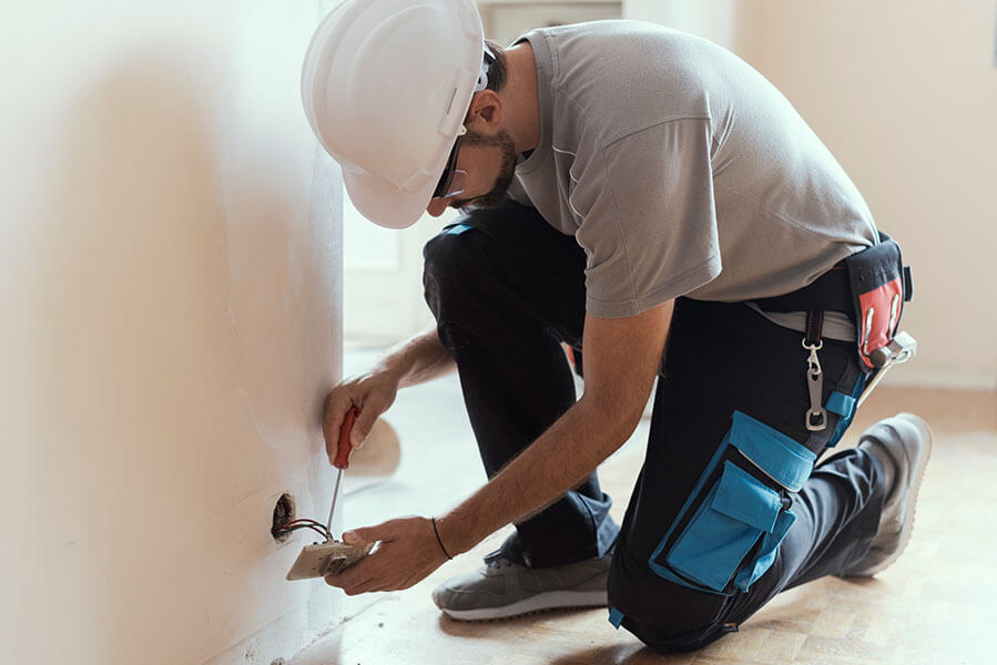 Professional electrician installing sockets using a screwdriver, home renovation and maintenance concept.