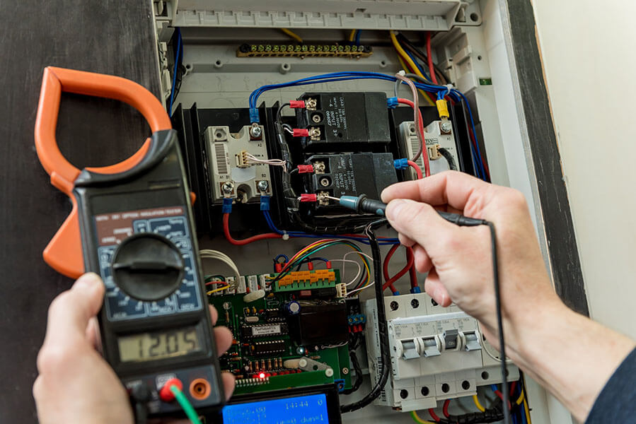 Close up of man's hands repairing switchboard voltage with automatic switches.