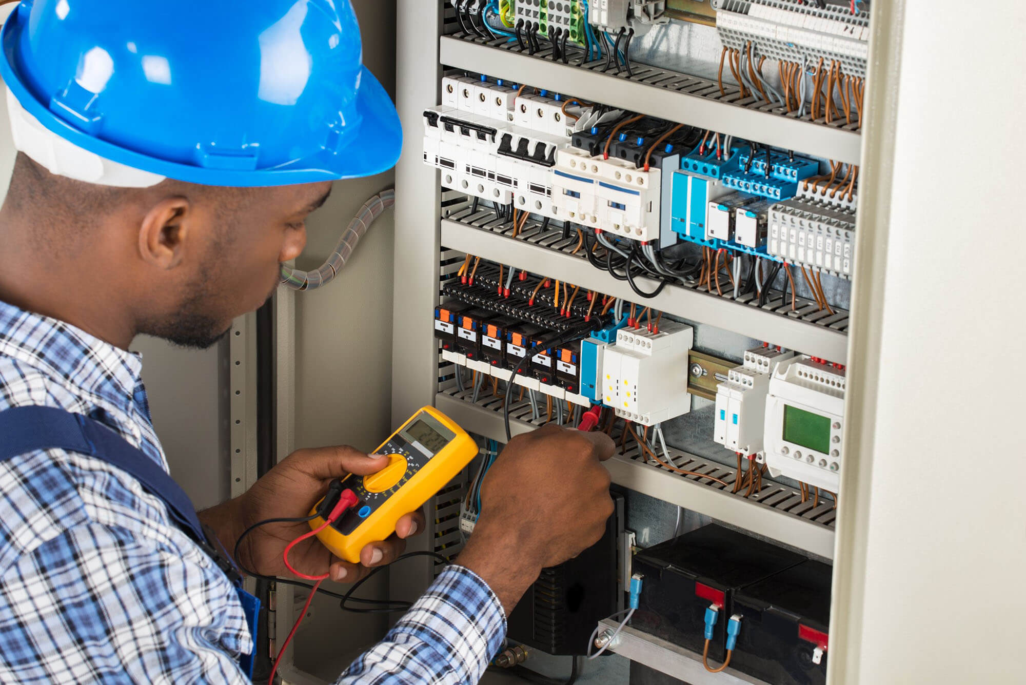 Male technician examining fusebox with multimeter probe